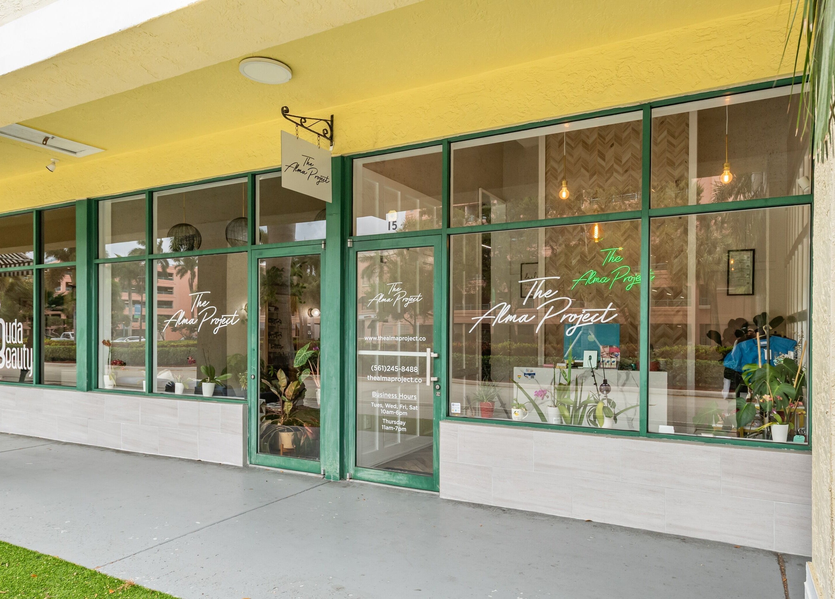 Front of The Alma Project by AG in Boca Raton, Florida, US with modern glass windows and vibrant signage.