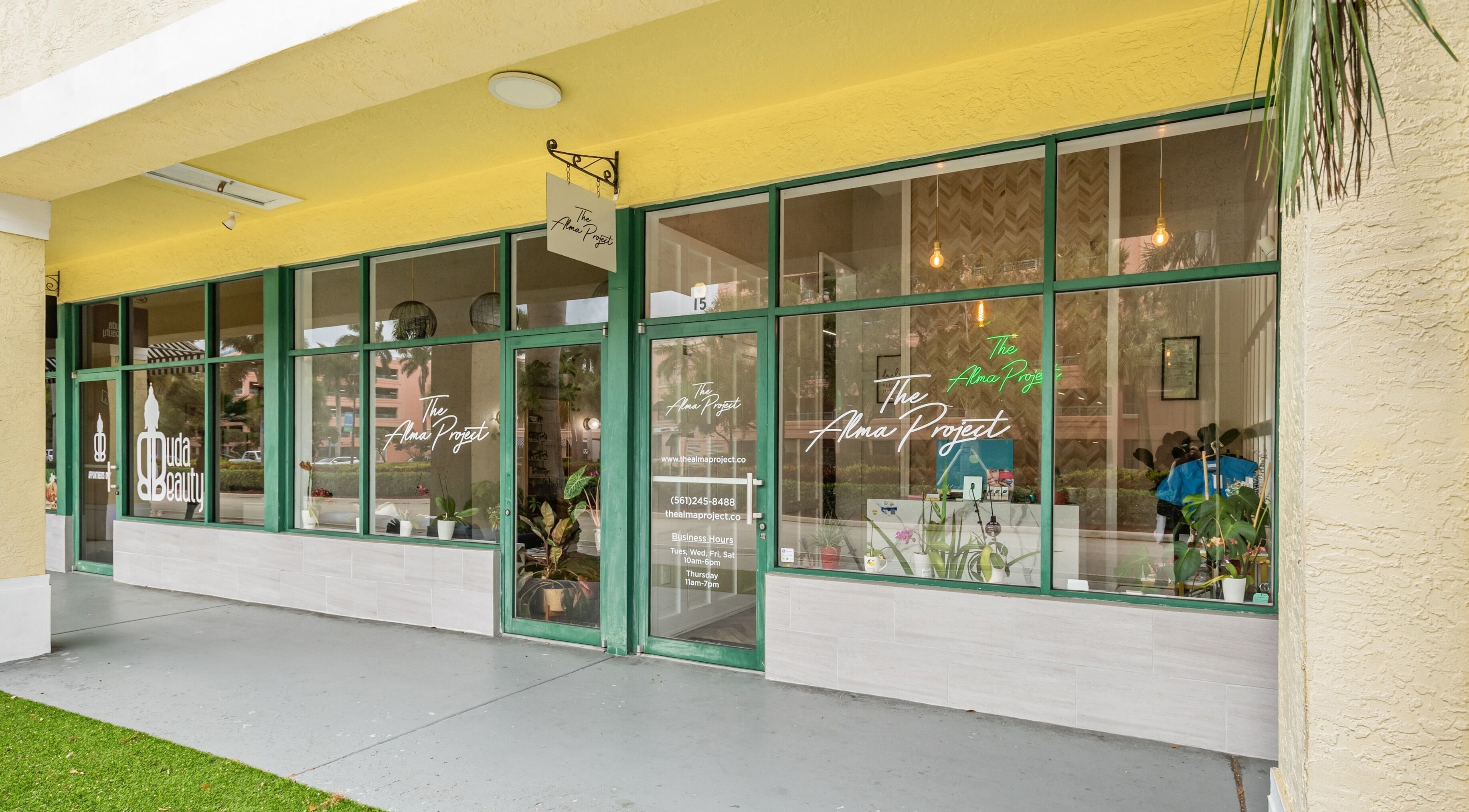 Front of The Alma Project by AG in Boca Raton, Florida, US with modern glass windows and vibrant signage.