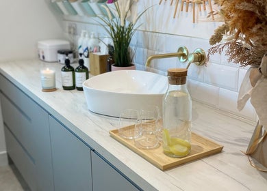 A tranquil vanity at Beauty + Wellness by Faye Jervis, Sheffield, England, GB, featuring a vessel sink, plants, and lemon water.