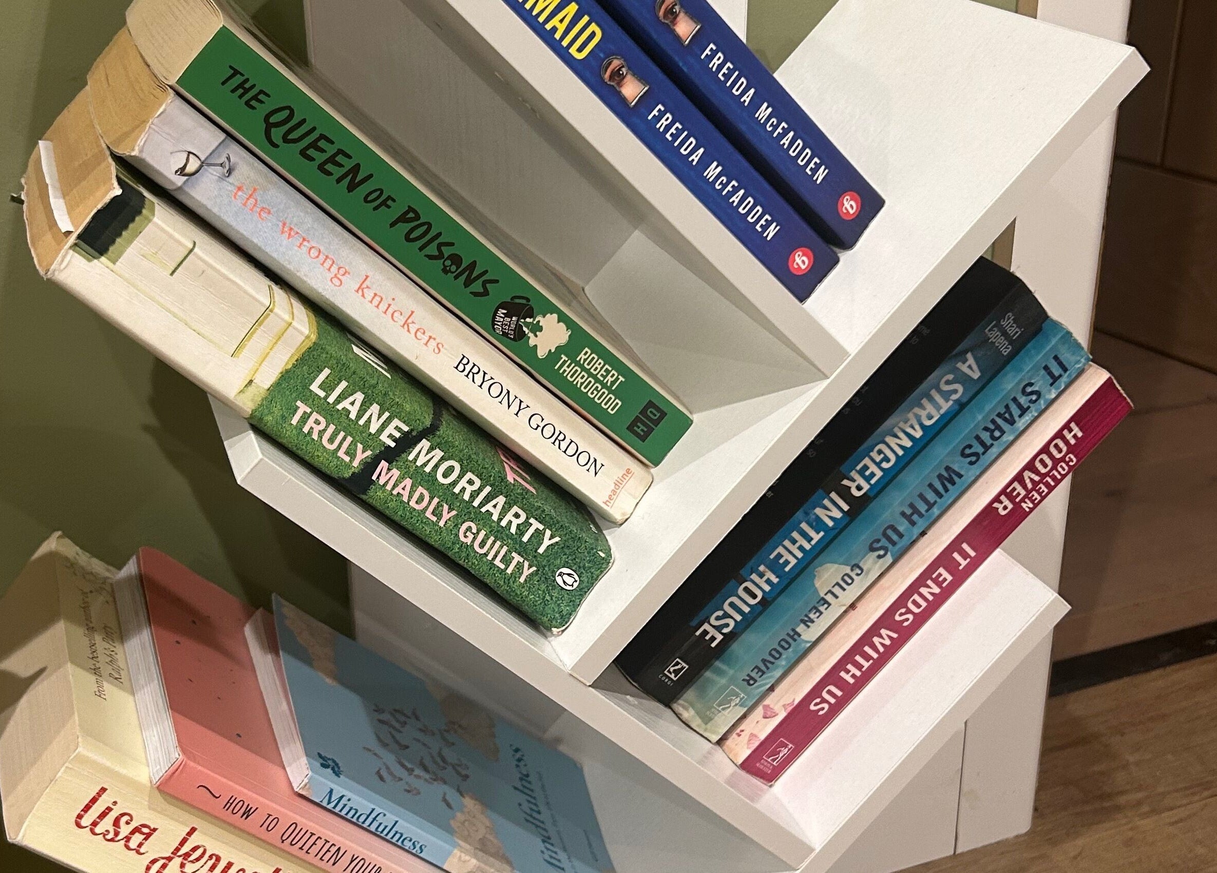 Cozy book corner at Salon Megan’s, Surrey, England, GB, featuring diverse reads on a modern white shelf.