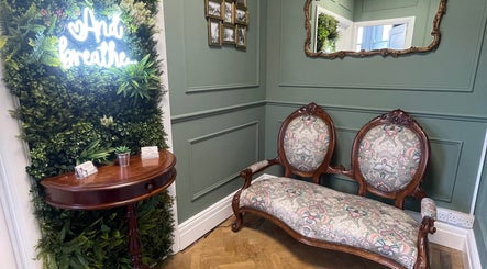 Elegant vintage seating and greenery wall at Rejuvenate Massage Therapy, Larne, Northern Ireland, GB.