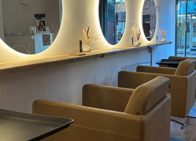 Elegant salon interior at Alice Olivia Hair, Alcester, England, GB, featuring plush chairs and illuminated mirrors.