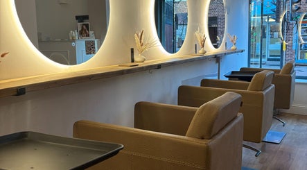 Elegant salon interior at Alice Olivia Hair, Alcester, England, GB, featuring plush chairs and illuminated mirrors.