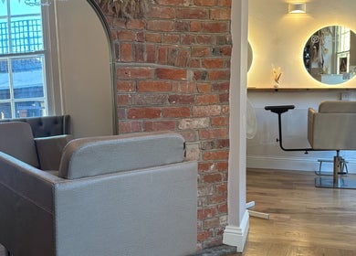 Stylish seating area inside Alice Olivia Hair, Alcester, England, GB, featuring modern decor and soft lighting.