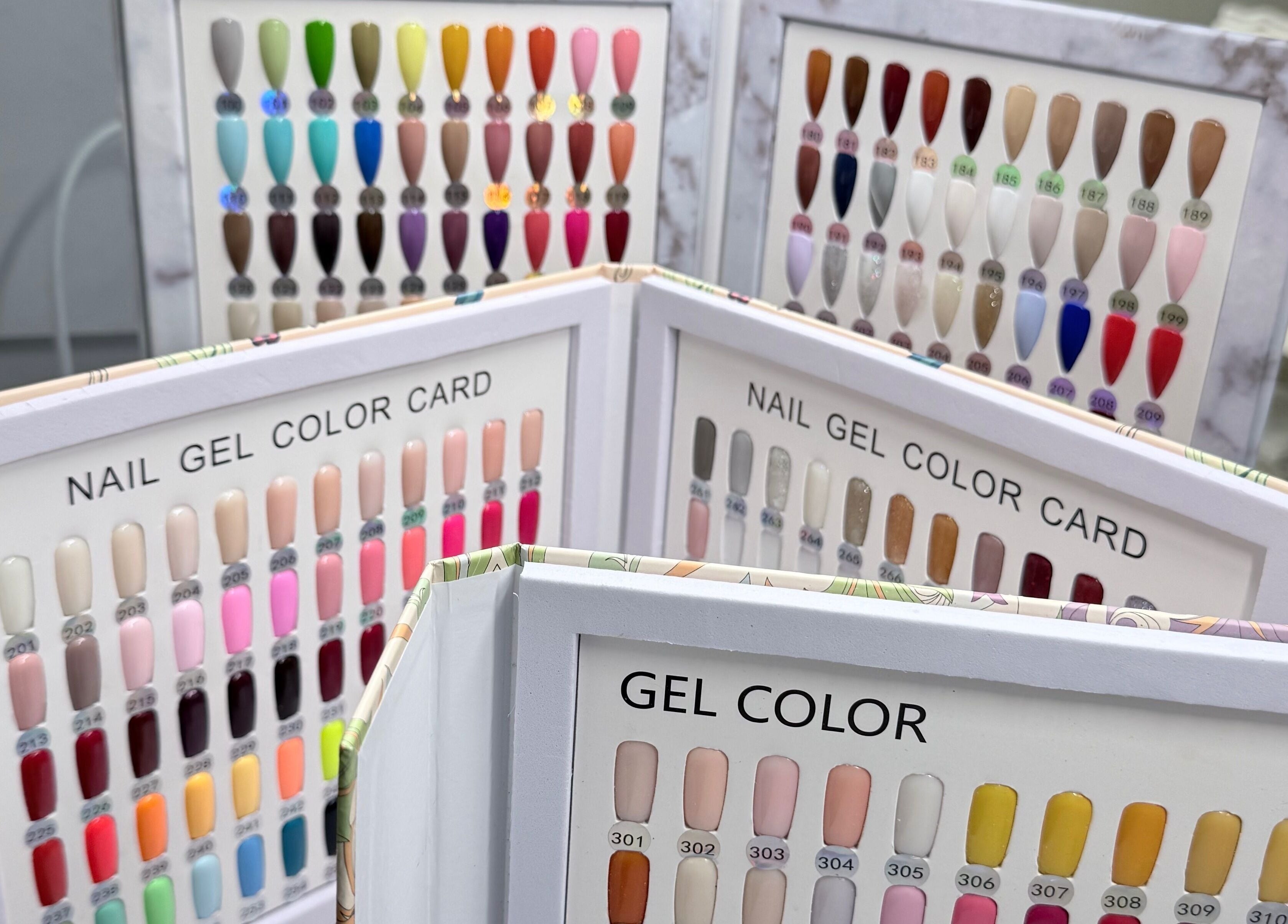 Colorful gel nail sample cards at Me Nail Spa, Alameda, California, US, showcasing various shades.