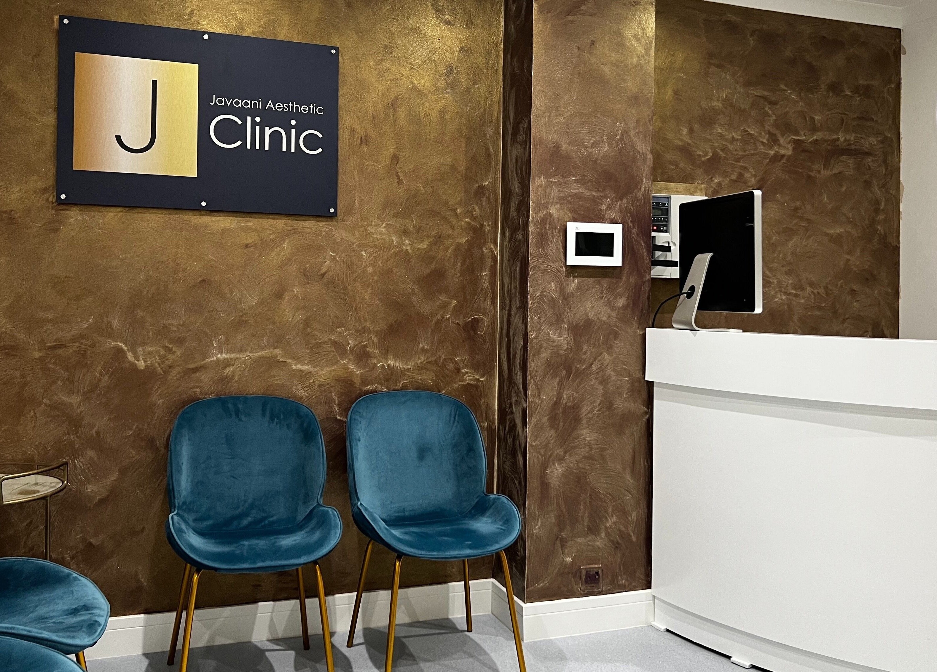 Reception area of Javaani Medical and Aesthetics, Hazlemere, England, GB with blue chairs and white desk.