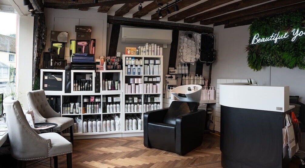 Interior of Beautiful You salon in Bures, England, GB with chic chairs and beauty products displayed.