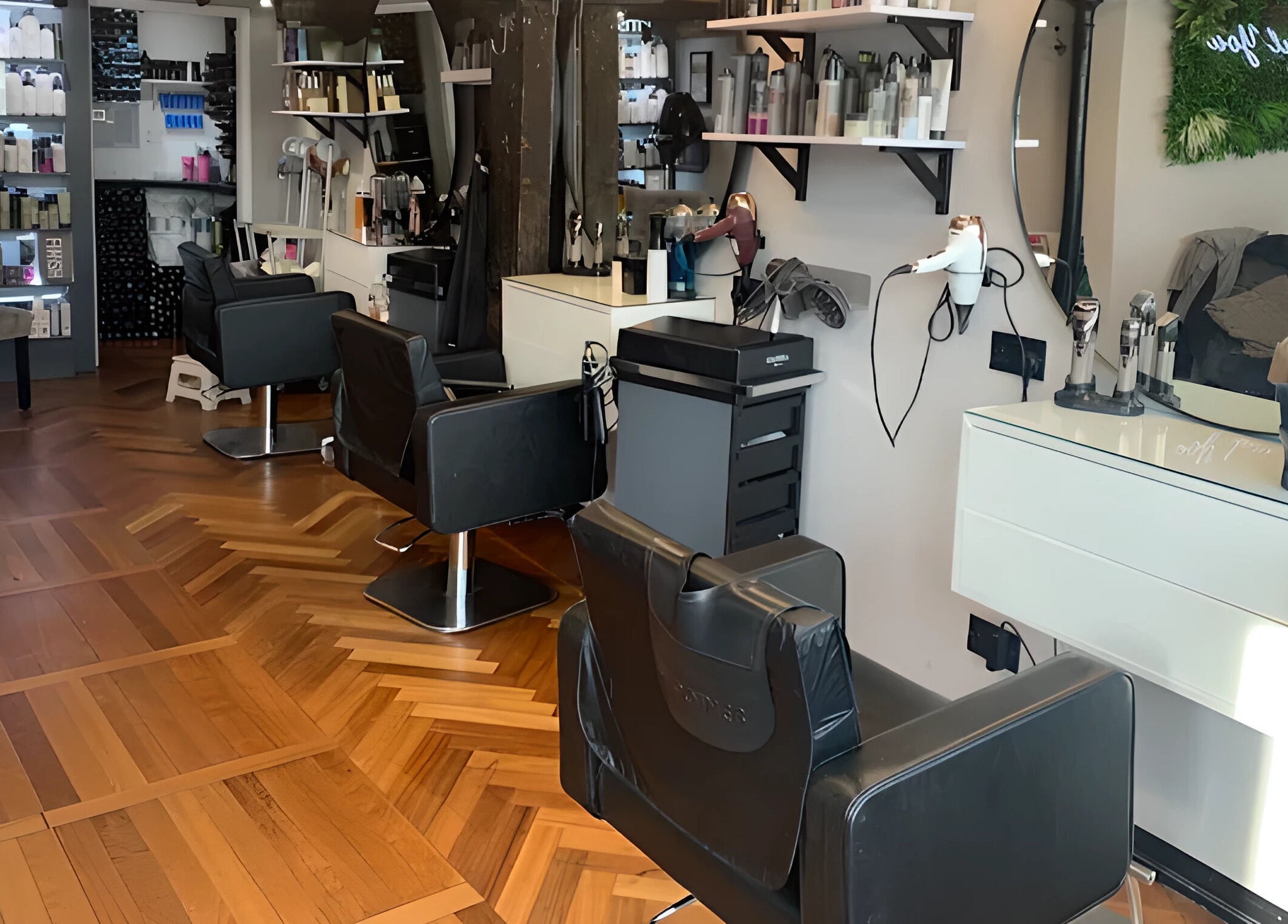 Modern salon interior at Beautiful You in Bures, England showcasing styling stations and shelving with products.