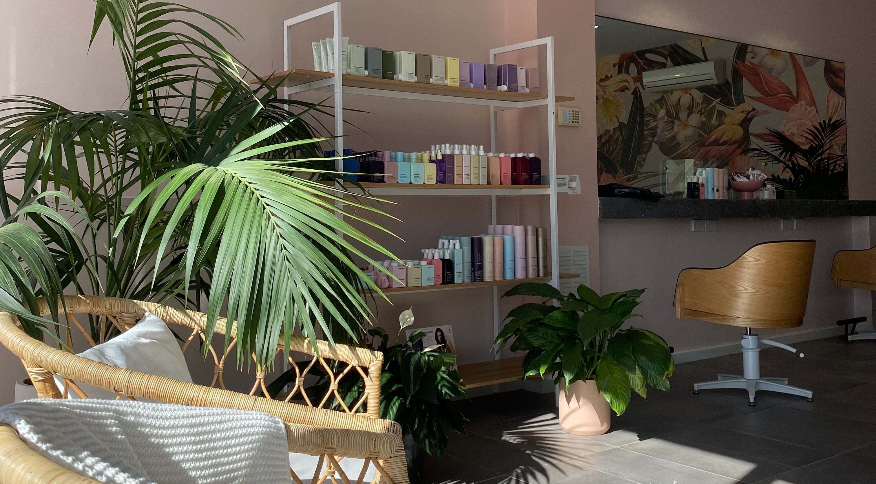 Inviting salon corner at Hair + Her, Gungahlin, Australian Capital Territory, AU with tropical plants and beauty products.