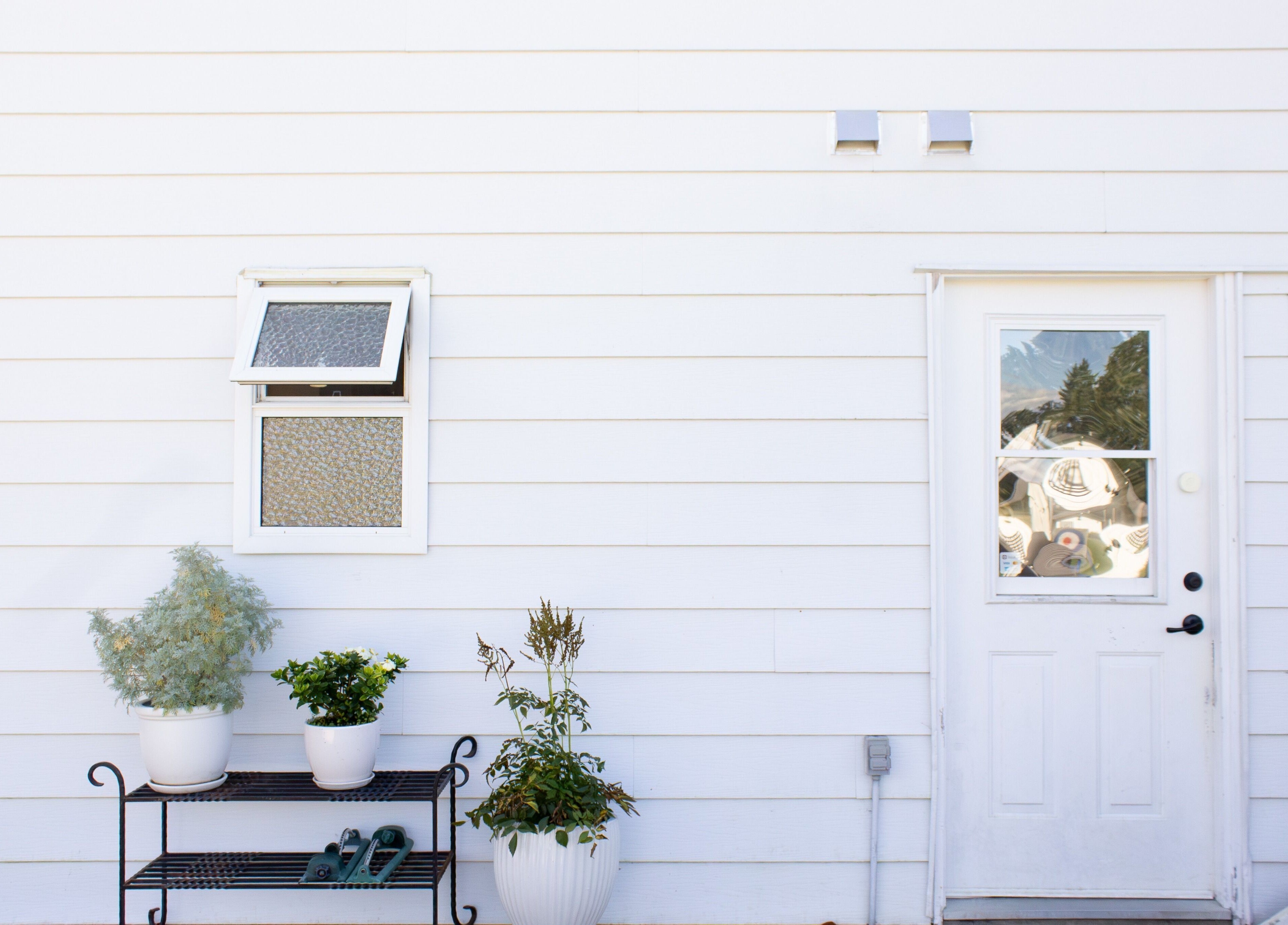 Entrance to Jessica Blackmon - Hairstylist in Langley City, BC, CA, with potted plants and white siding.