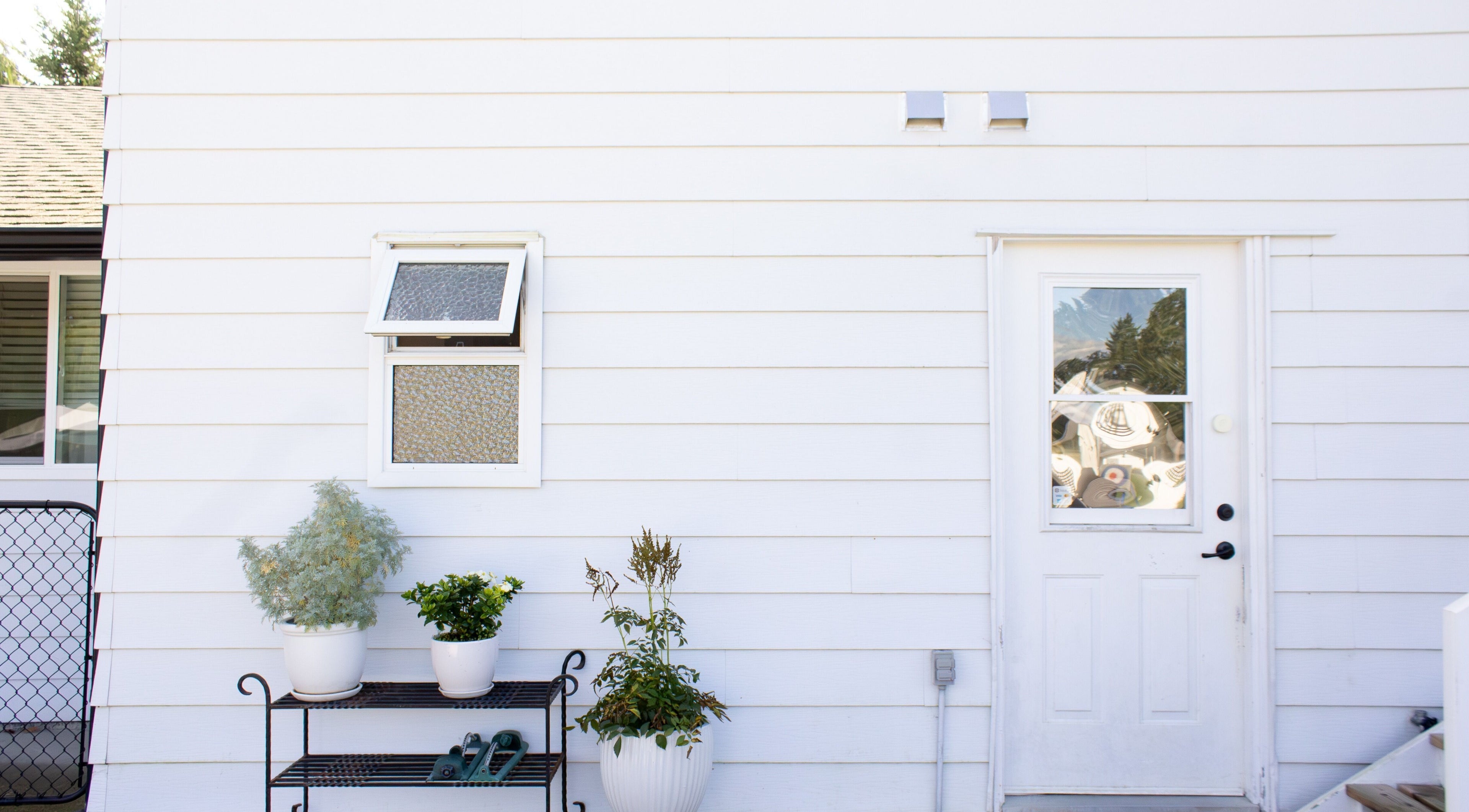 Entrance to Jessica Blackmon - Hairstylist in Langley City, BC, CA, with potted plants and white siding.