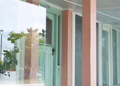 Elegant glass façade of Katie Jones Hair in Windsor, Queensland, AU, reflecting the serene street view.
