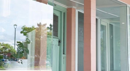 Elegant glass façade of Katie Jones Hair in Windsor, Queensland, AU, reflecting the serene street view.