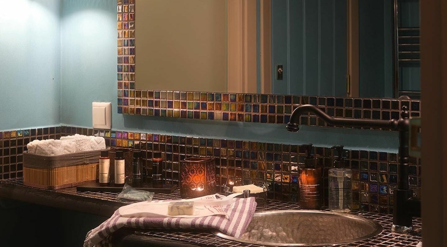 Elegant sink area at Eressian Hammam and Spa in Ερεσός, GR, with mosaic tiles and spa products.