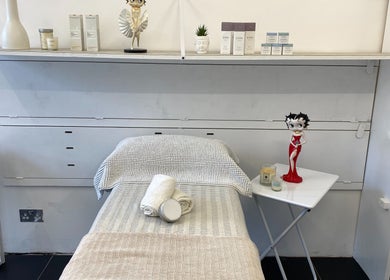 Cozy treatment room at GlamLift, Edinburgh, Scotland, GB, featuring a massage table with towels and decorative items.