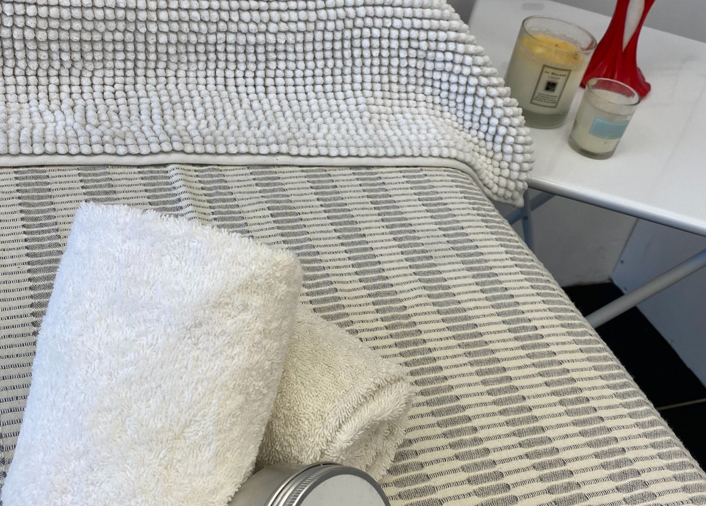 Cozy treatment bed with towels and candles at GlamLift in Edinburgh, Scotland, GB.