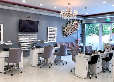 Elegant interior of The Nail Company in London, England, GB featuring plush chairs and floral decor.