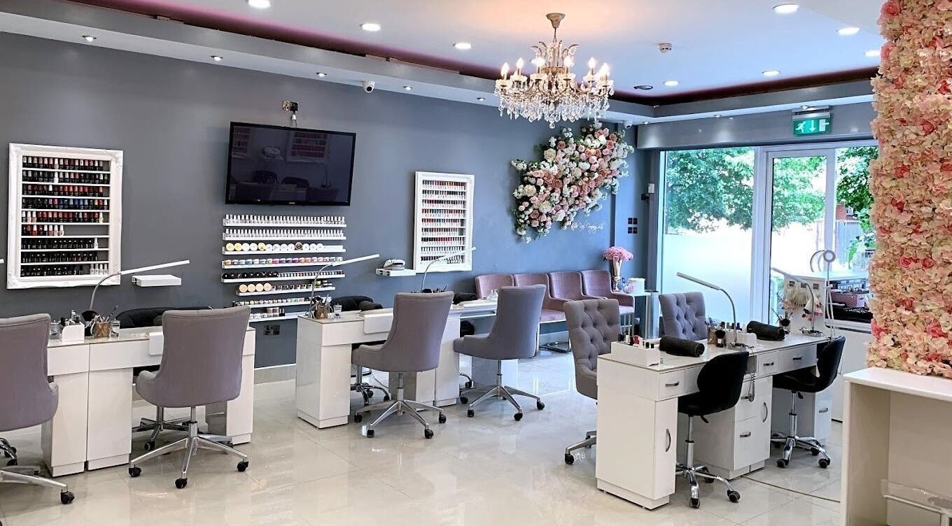 Elegant interior of The Nail Company in London, England, GB featuring plush chairs and floral decor.