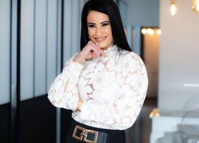 Elegant woman smiling at Face & Body Studio SA in Boksburg, Gauteng, ZA, with modern decor and soft lighting.