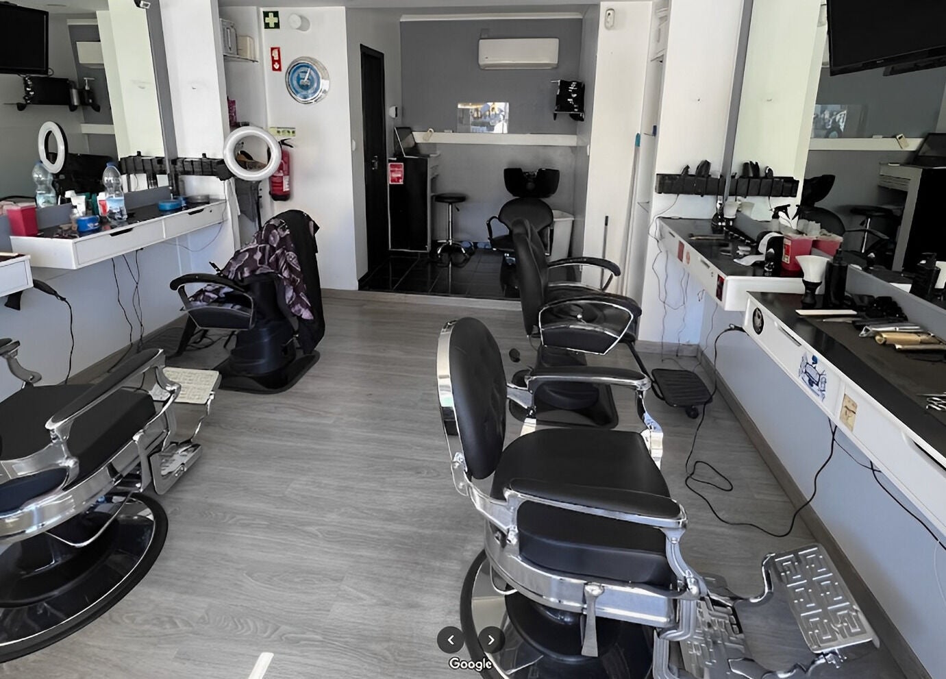 Interior moderno do Fabiu's Barbershop Cascais, em Cascais, Lisboa, PT, com cadeiras de barbeiro pretas e espelhos.