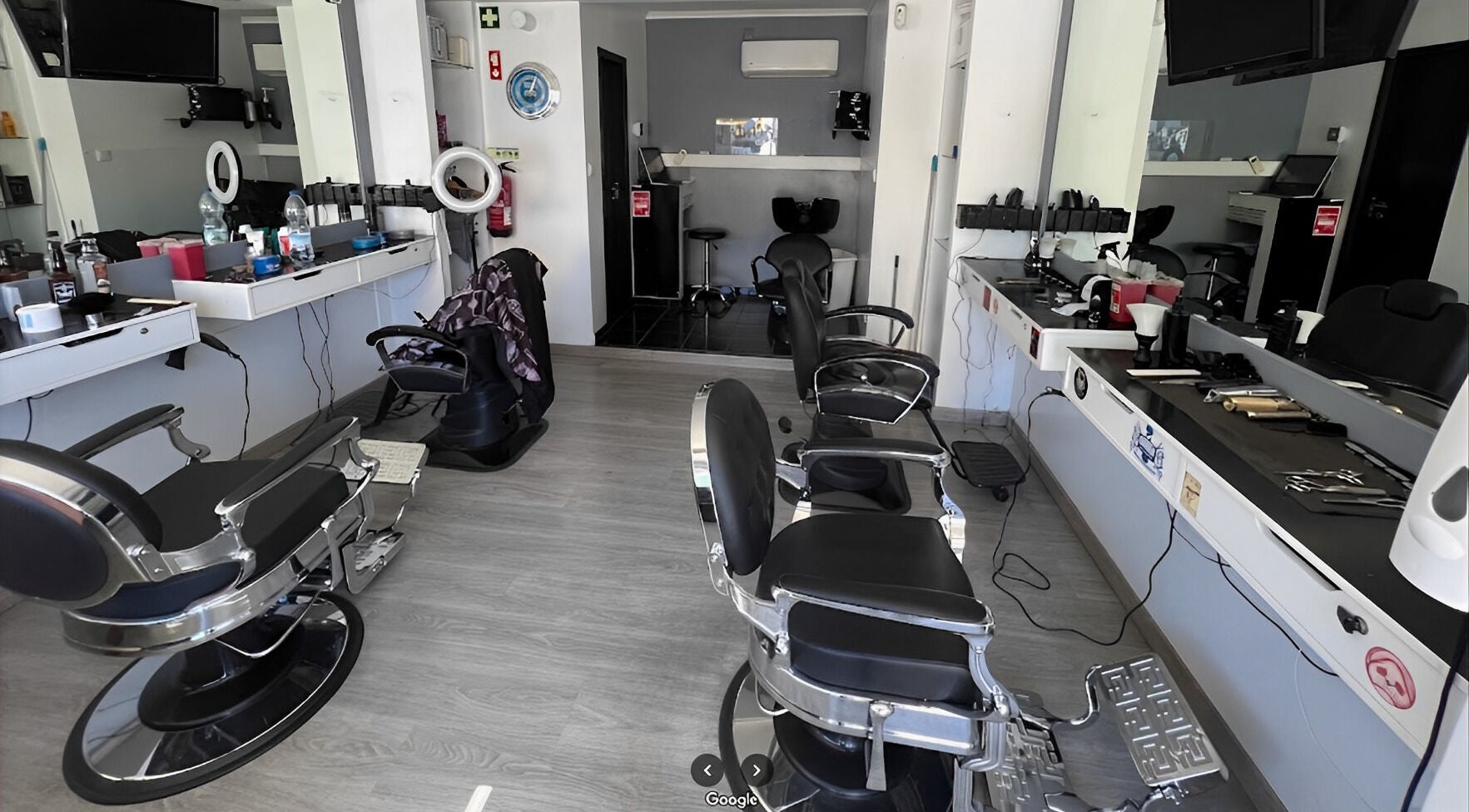 Interior moderno do Fabiu's Barbershop Cascais, em Cascais, Lisboa, PT, com cadeiras de barbeiro pretas e espelhos.