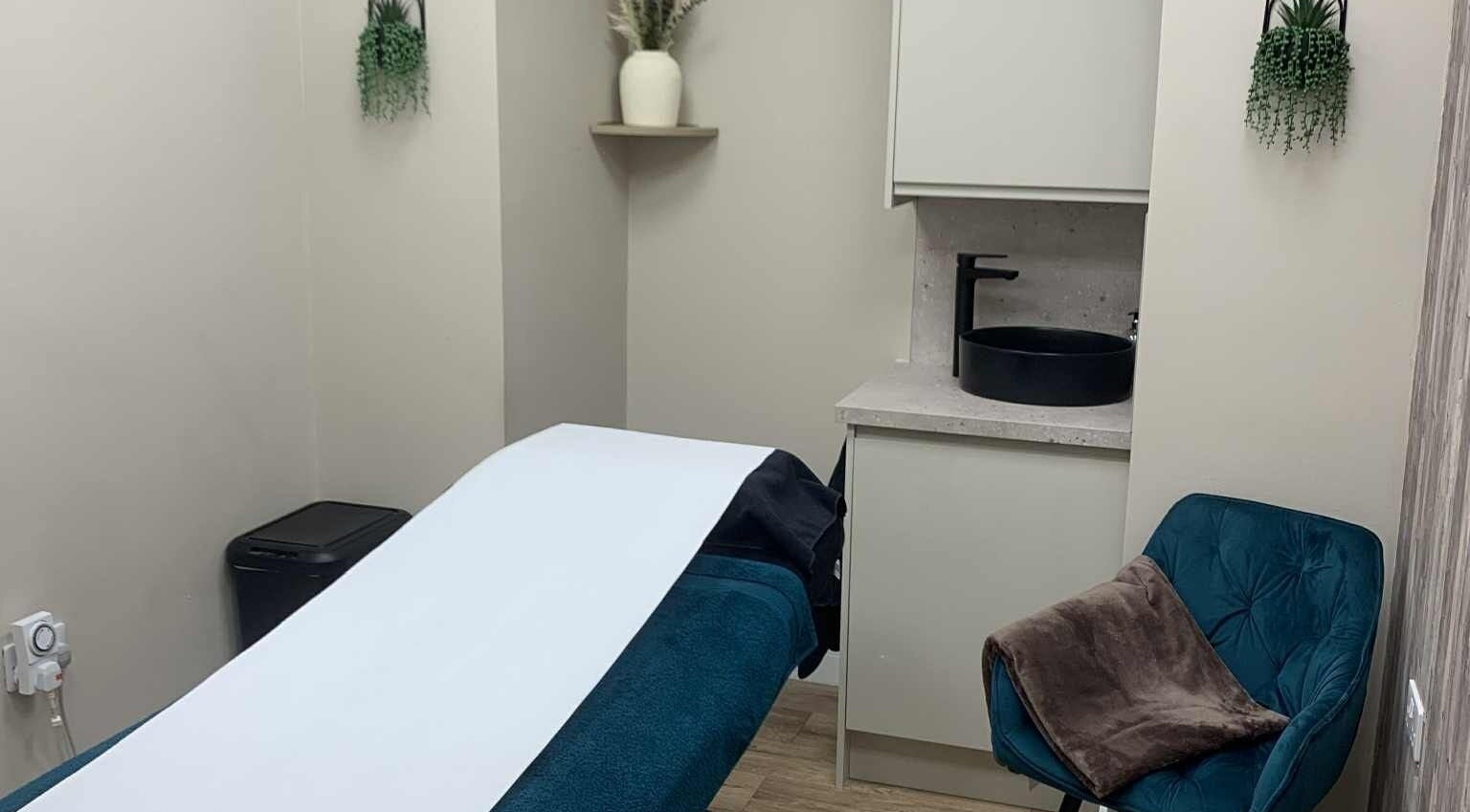 Treatment room at Ruth's Retreat in Douglas, GB, featuring a massage bed, modern decor, and calming ambiance.