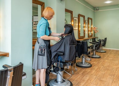Stylist attending client at Lisa Hauck salon, London, England, GB. Modern, elegant hairdressing interior.
