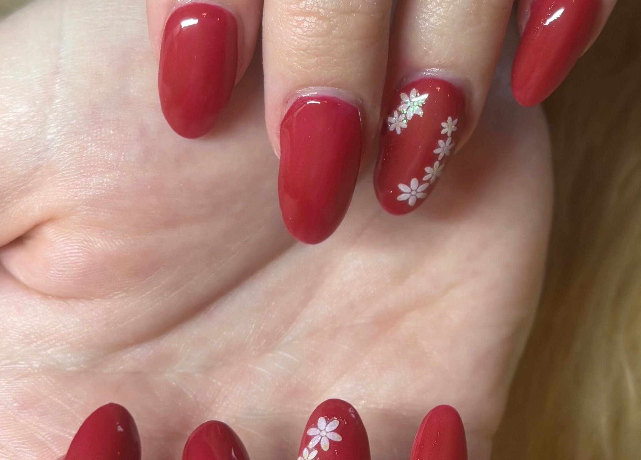 Elegant red manicure with floral design at Twinkle Toes and Fingers & Aesthetics, Taverham, England, GB.