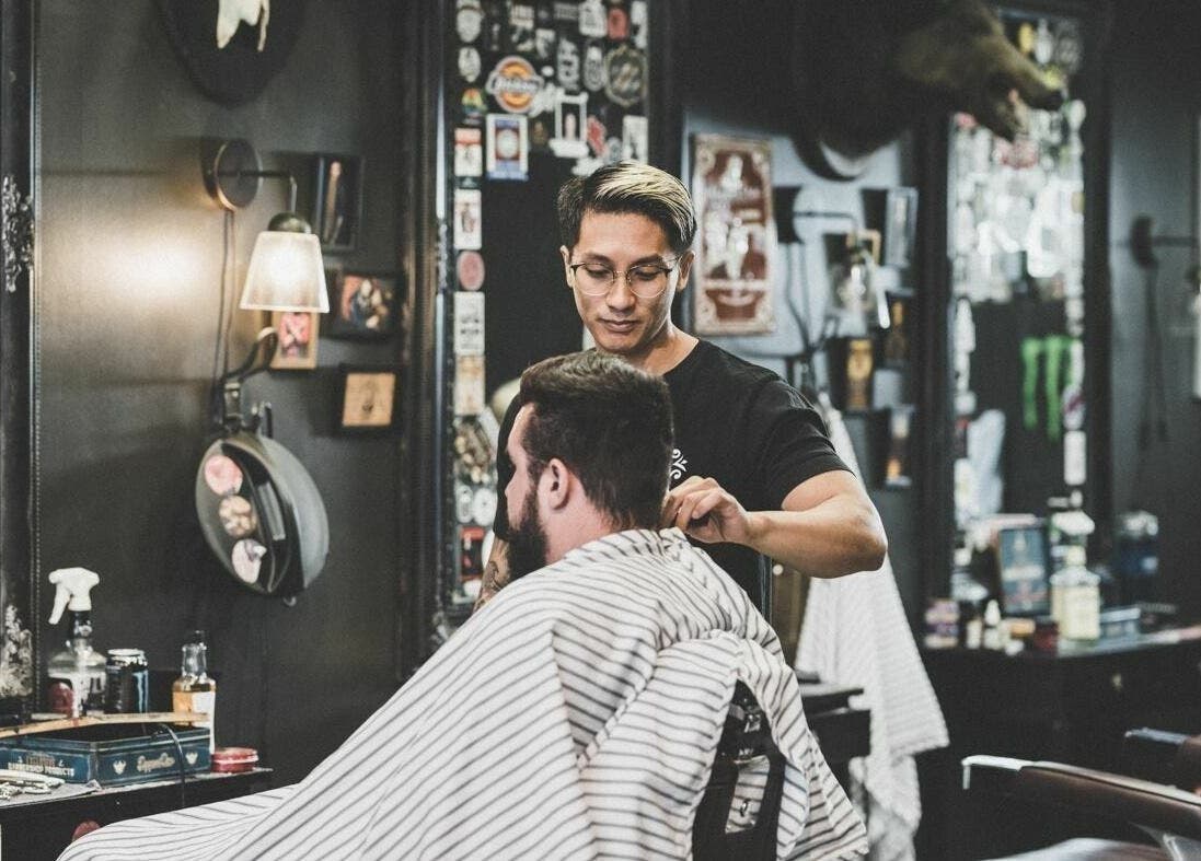 Barber styling a man's hair at Dick Johnson | Turku, Turku, FI, with a vintage interior.