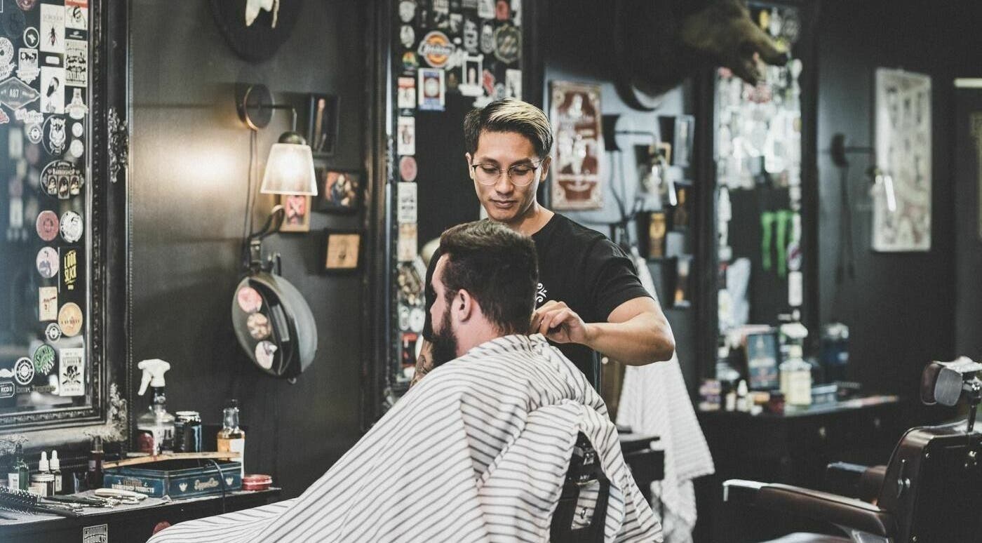 Barber styling a man's hair at Dick Johnson | Turku, Turku, FI, with a vintage interior.