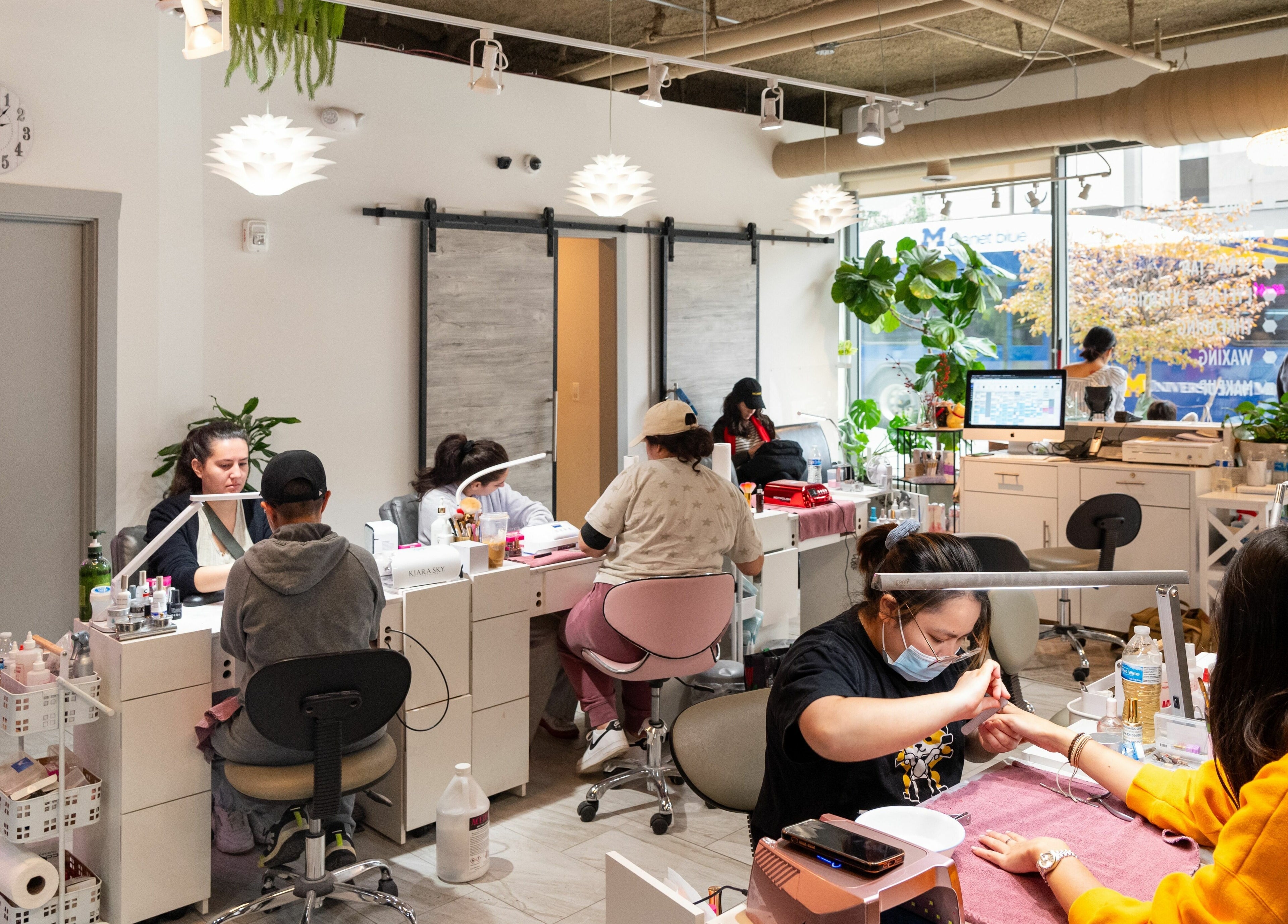 Inside BeeQ Downtown A2 in Ann Arbor, Michigan, US, showcasing a lively nail salon with clients and staff.