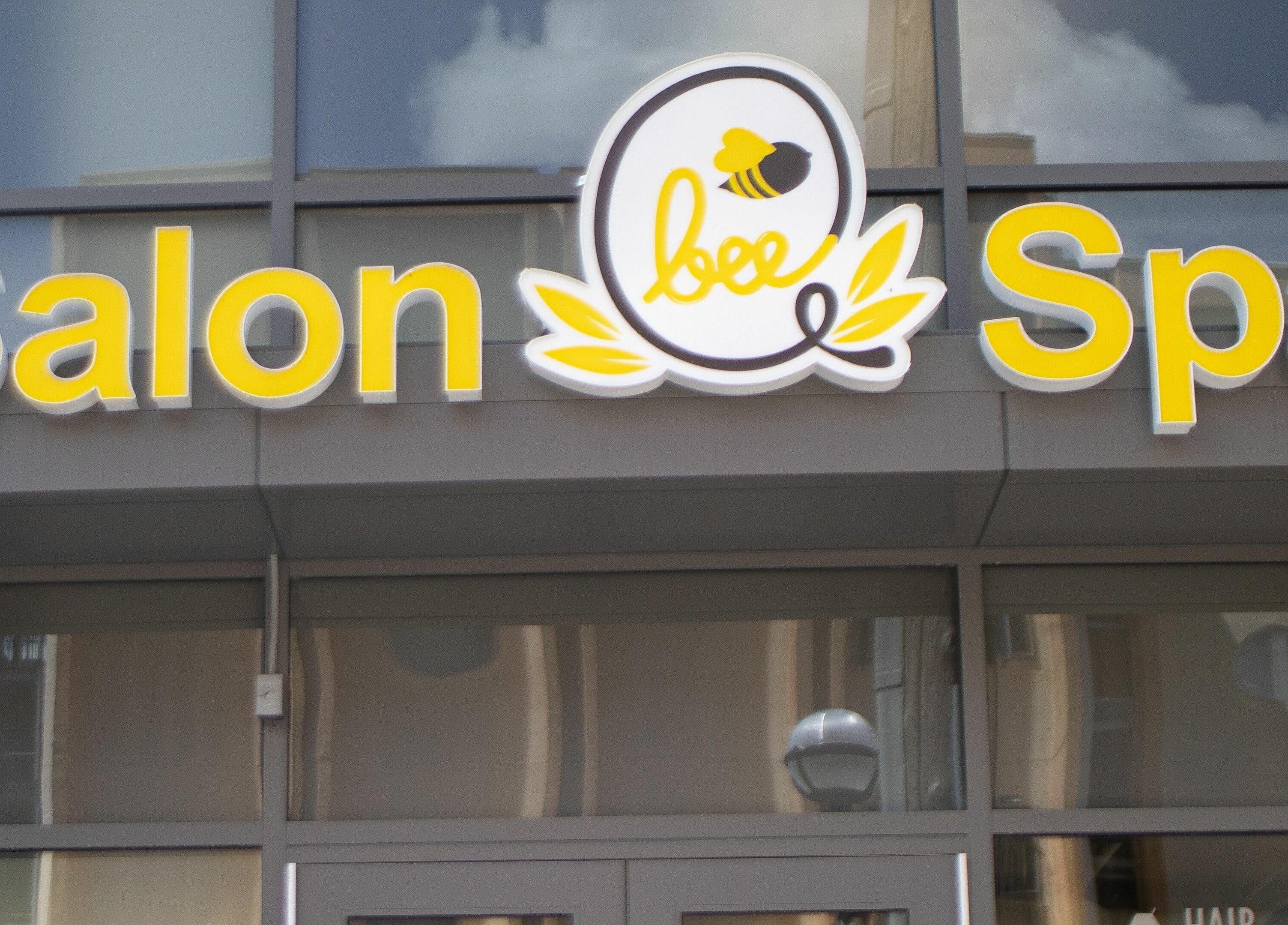 BeeQ Downtown A2 salon and spa exterior signage in Ann Arbor, Michigan, US with yellow lettering.
