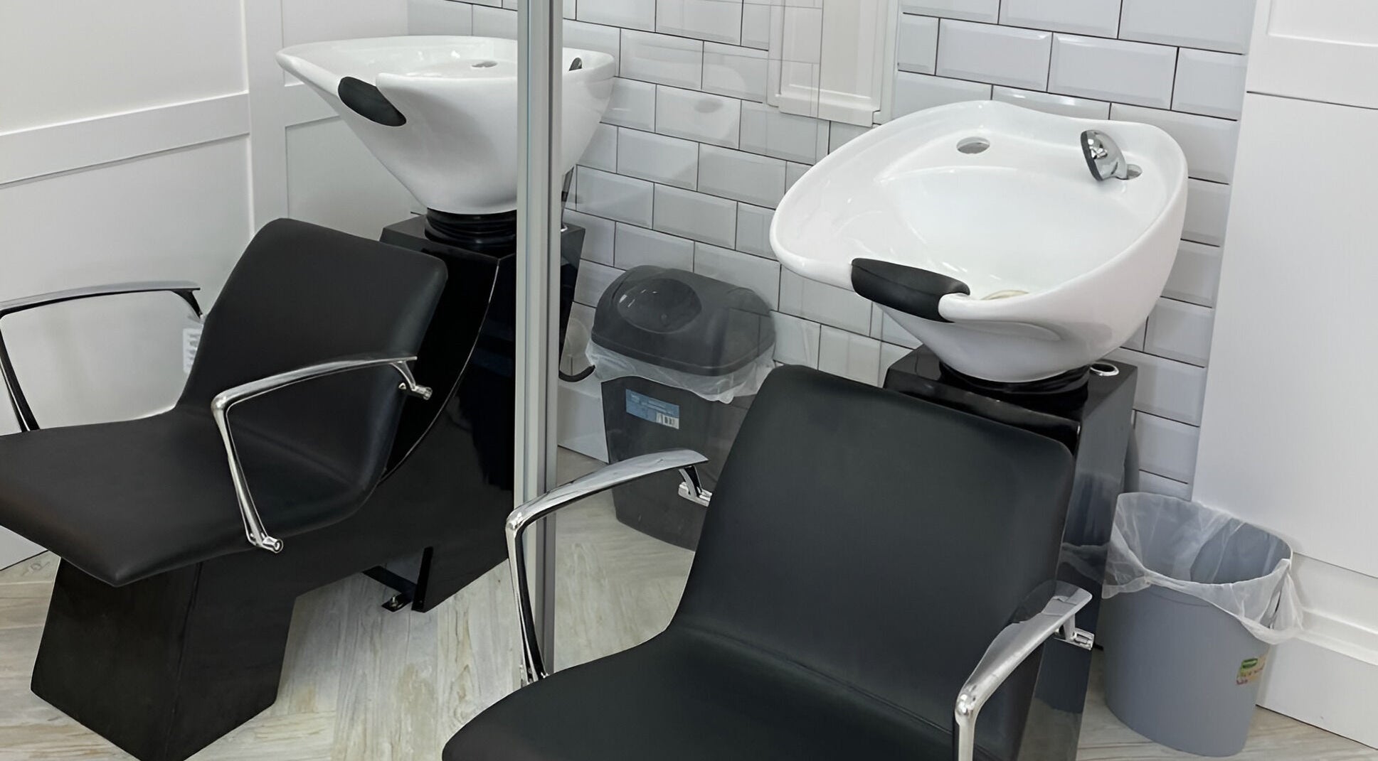 Modern wash stations at Visions Hair Studio, Manchester, England, GB. Sleek black chairs and white sinks.