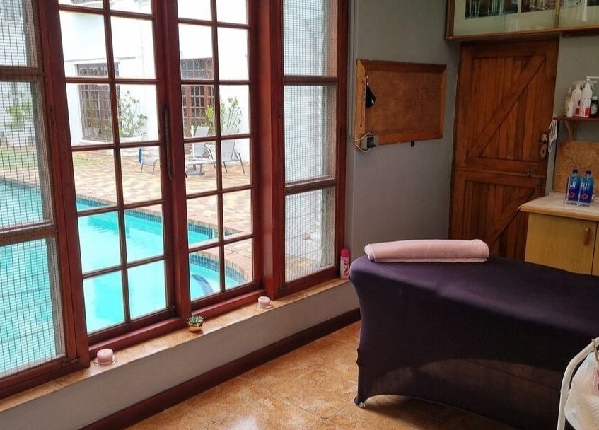 Relaxation room at The Brow Room, Port Elizabeth, Eastern Cape, ZA with pool view through large windows.