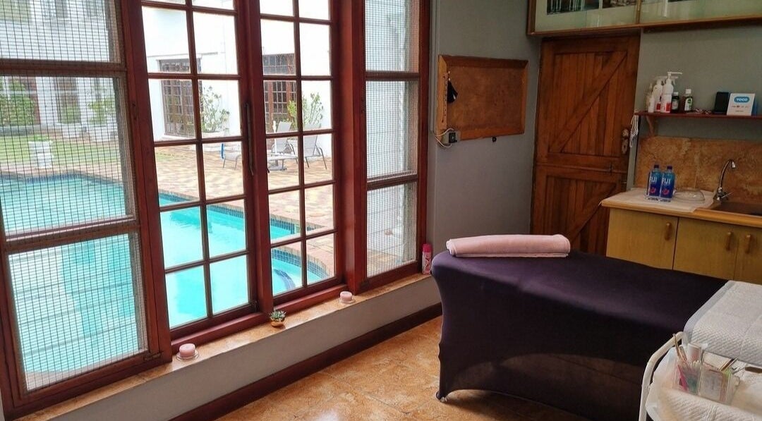 Relaxation room at The Brow Room, Port Elizabeth, Eastern Cape, ZA with pool view through large windows.