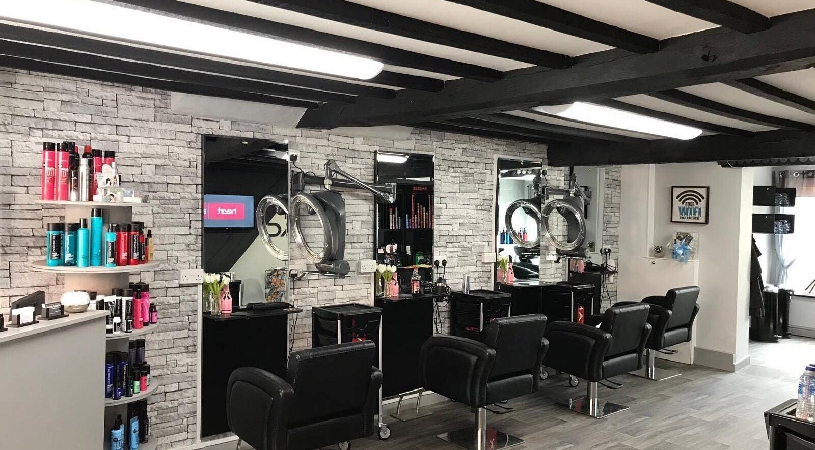 Modern salon interior at Jet Black, Dereham, England, GB with sleek black chairs and stylish product display.