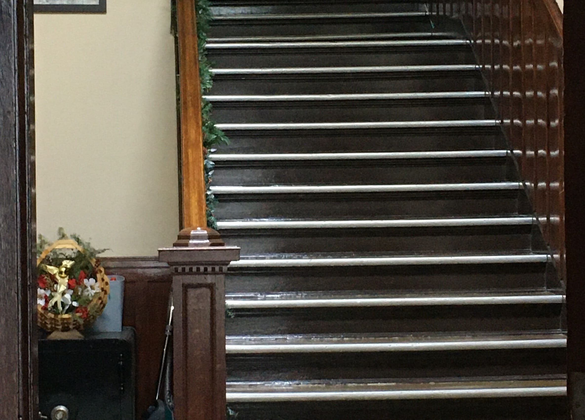 Wooden staircase at Free at Last, Thunder Bay, Ontario, CA, adorned with greenery and floral basket.