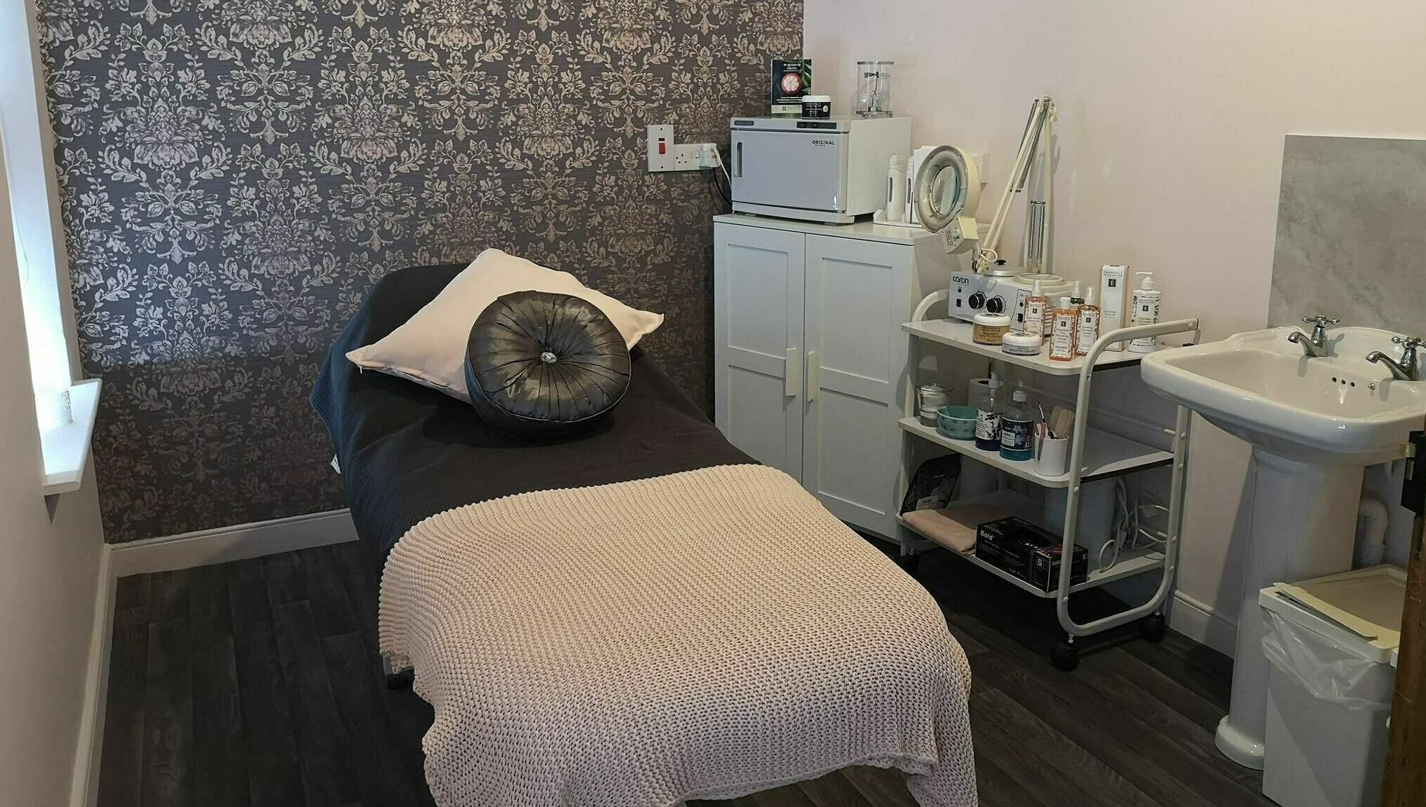 Serene treatment room at Still Beauty, Rathdowney, County Laois, IE with plush bed and skincare products.