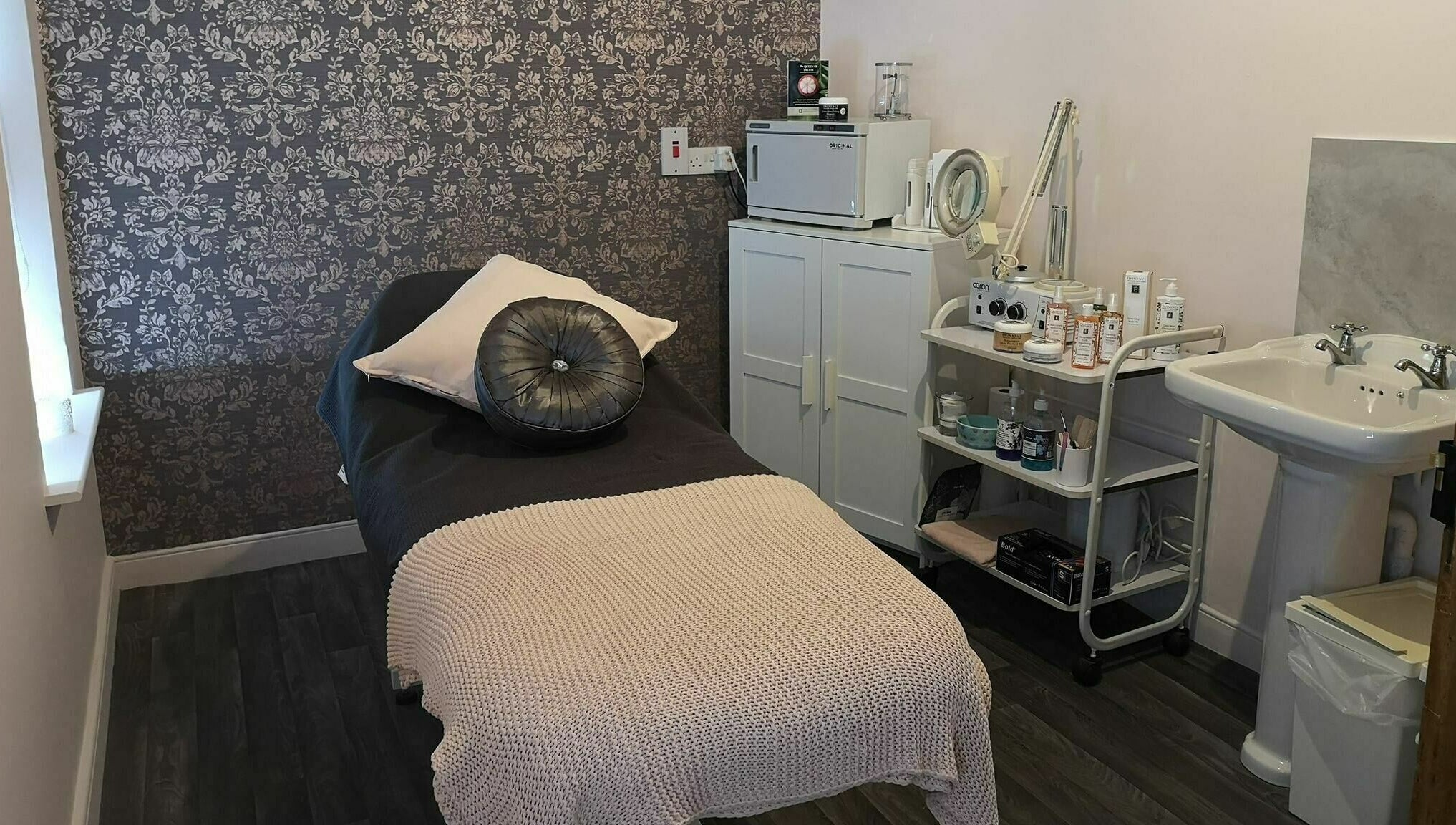 Serene treatment room at Still Beauty, Rathdowney, County Laois, IE with plush bed and skincare products.