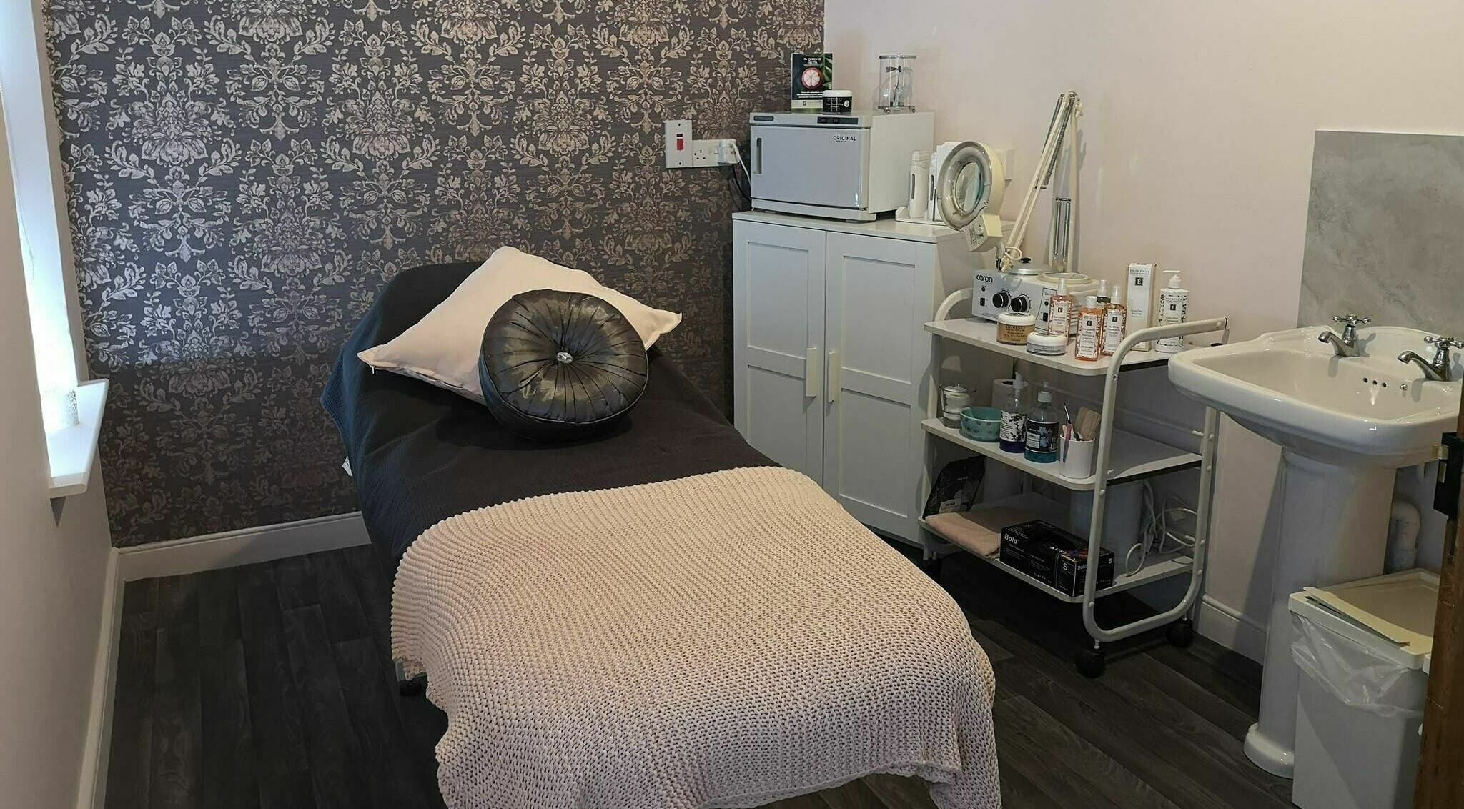 Serene treatment room at Still Beauty, Rathdowney, County Laois, IE with plush bed and skincare products.