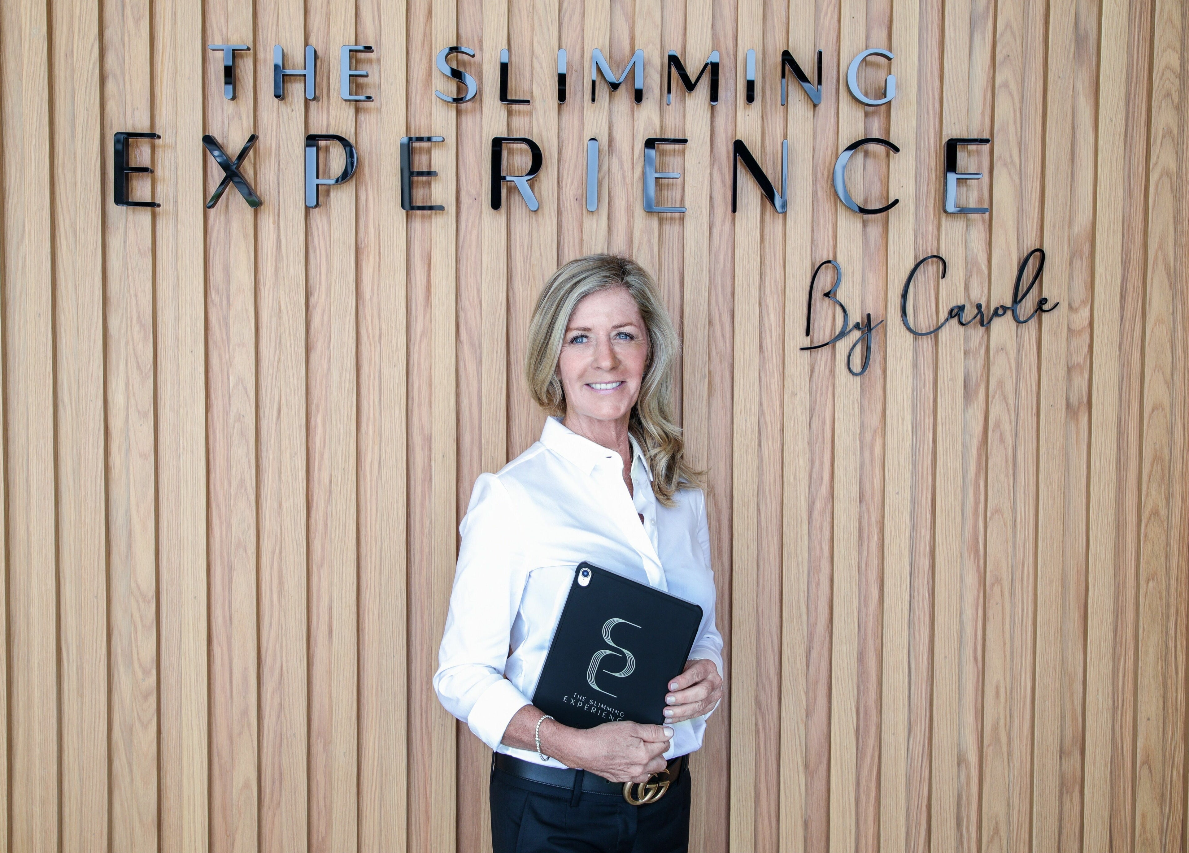 Professional woman at The Slimming Experience in Dubai, Dubai, AE, by a branded wooden wall.
