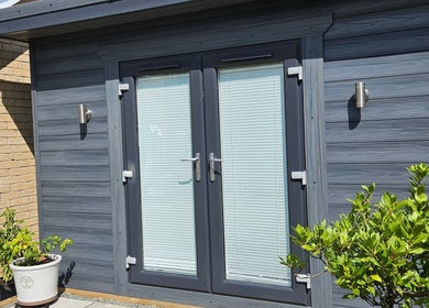 Modern entrance to The Beauty Room in Peterborough, England, GB with sleek glass doors and vibrant greenery.