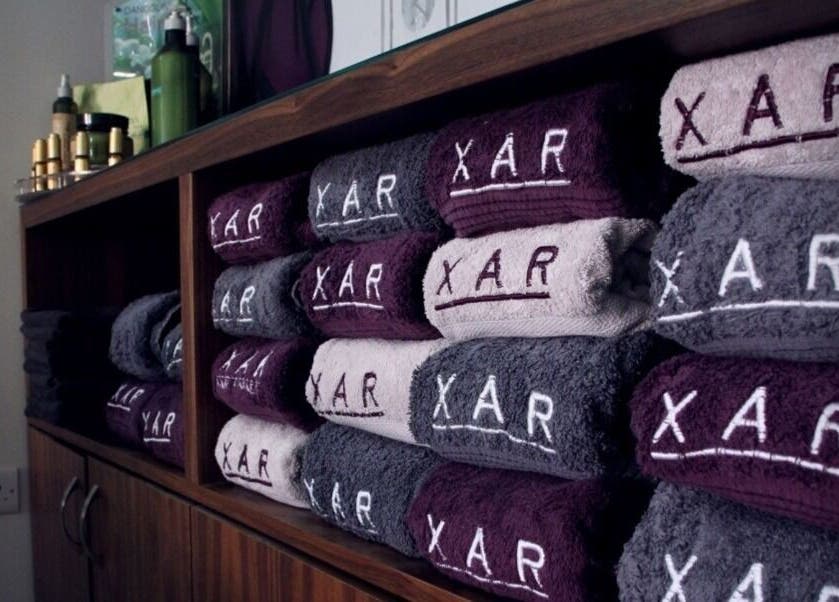 Stacked branded towels at Xar Hair & Nails, Is-Swieqi, MT showcasing luxury and quality.