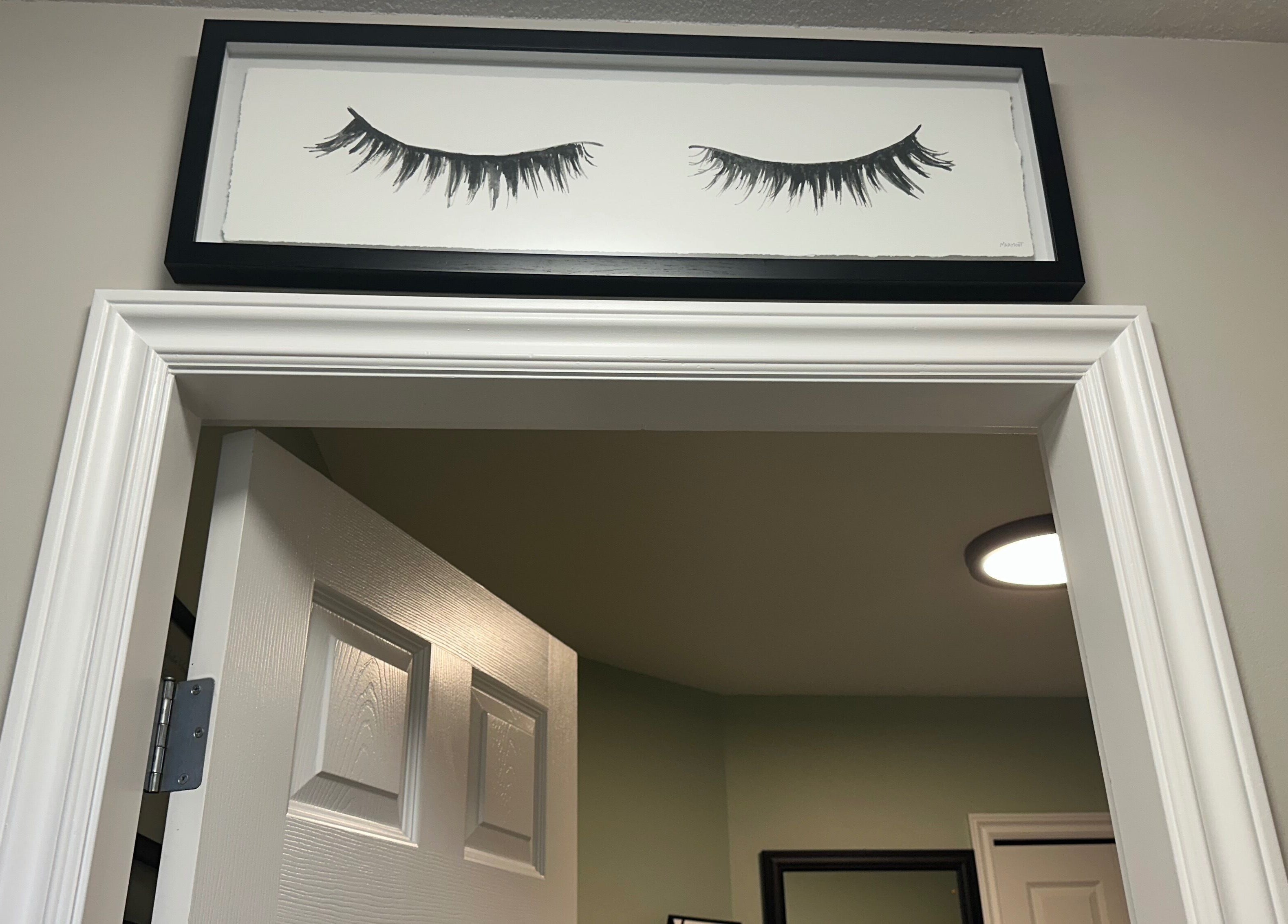 Framed eyelash art above door at Honey Lashes by V, Nanaimo, BC, enhances welcoming ambiance.