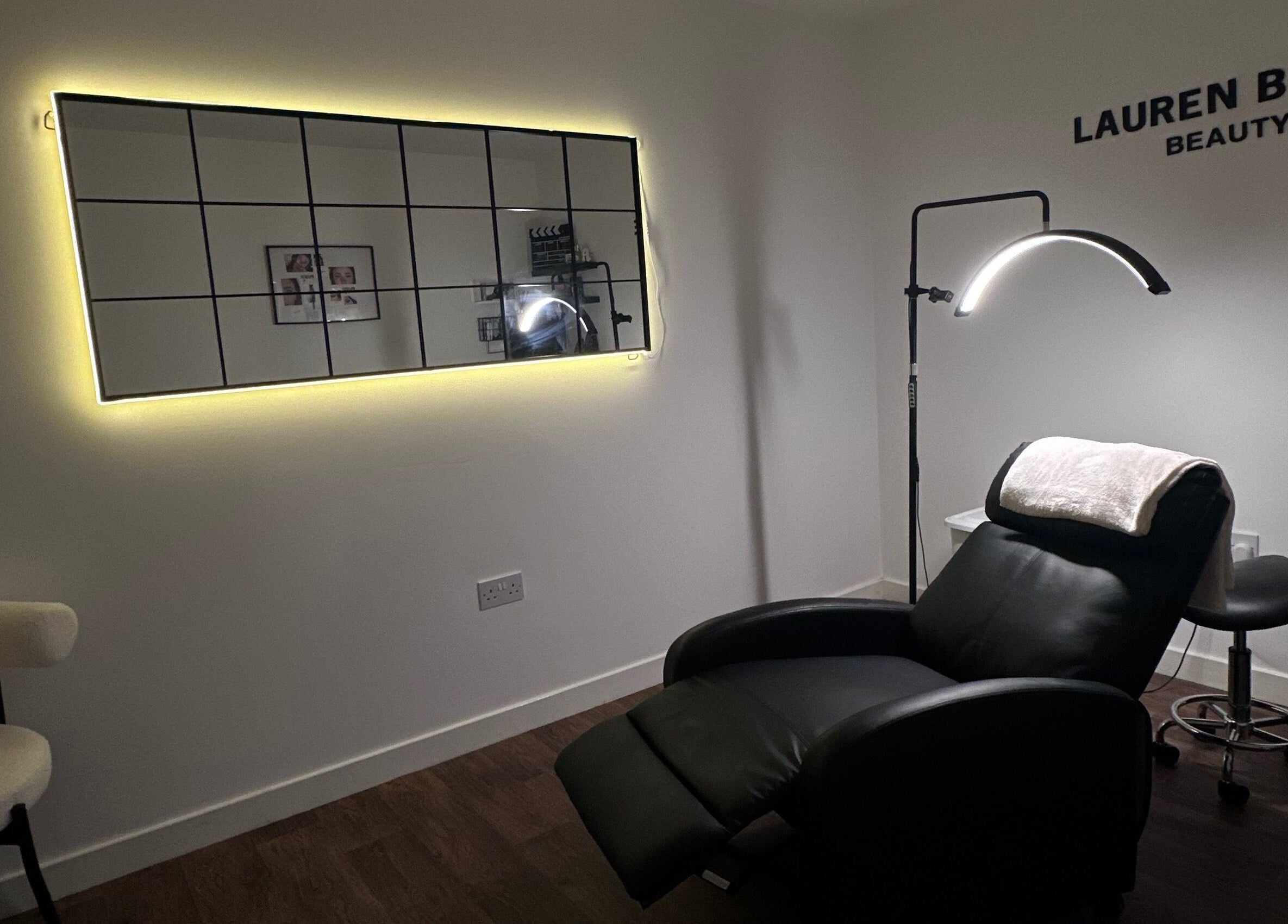 Modern beauty treatment room at The Brow Barn, Middleton, England, GB, featuring a sleek chair and glowing mirror.