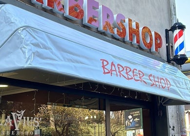 Ingresso di Flavius’Barbershop a Roma, Lazio, IT con insegna e palo da barbiere tradizionale.