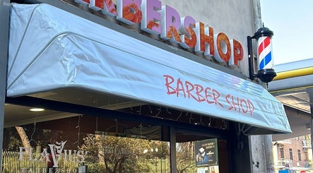Ingresso di Flavius’Barbershop a Roma, Lazio, IT con insegna e palo da barbiere tradizionale.