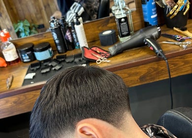 Taglio di capelli moderno a Flavius’ Barbershop, Roma, Lazio, IT. Strumenti da barbiere sullo sfondo.
