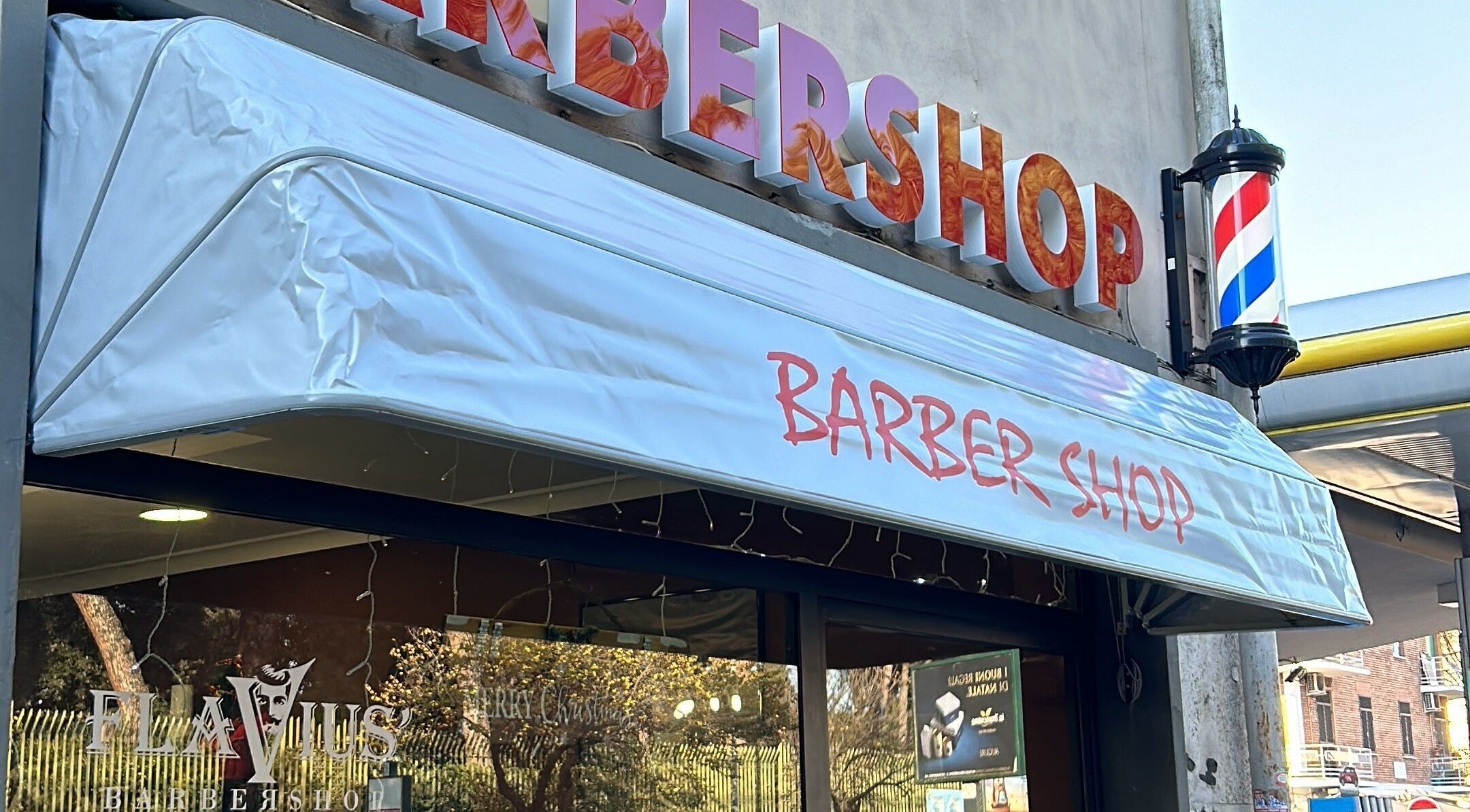 Insegna di Flavius’ Barbershop Tuscolana, Roma, Lazio, IT, con caratteristico palo da barbiere.