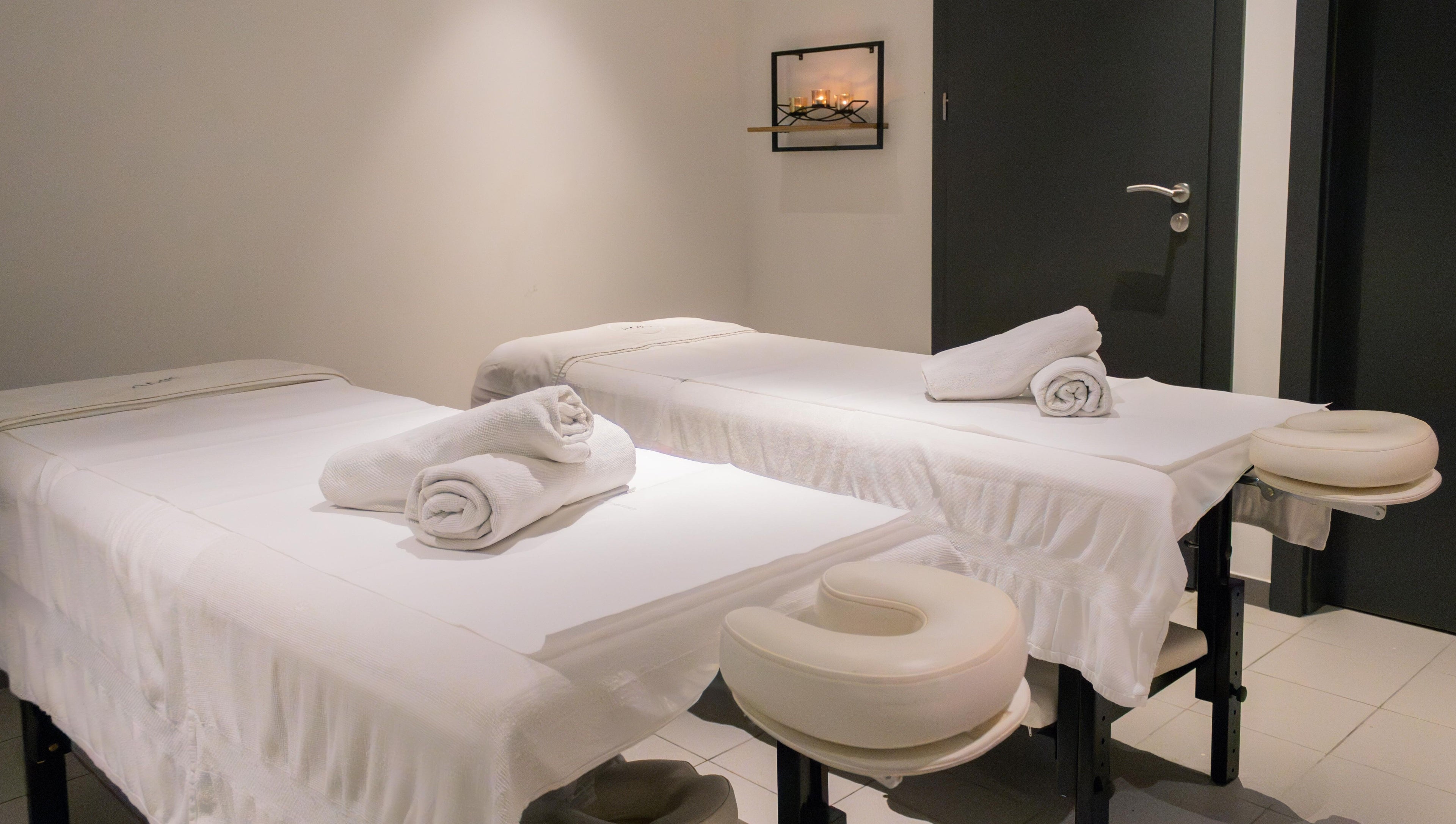 Relaxing spa room at AMIS @ The Embassy Hotel, Valletta, MT, featuring two massage tables with fresh towels.